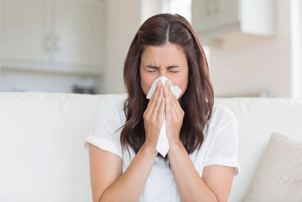 Woman sneezing into tissue suffering from allergic rhinitis and nasal congestion at Center of ENT Lahore