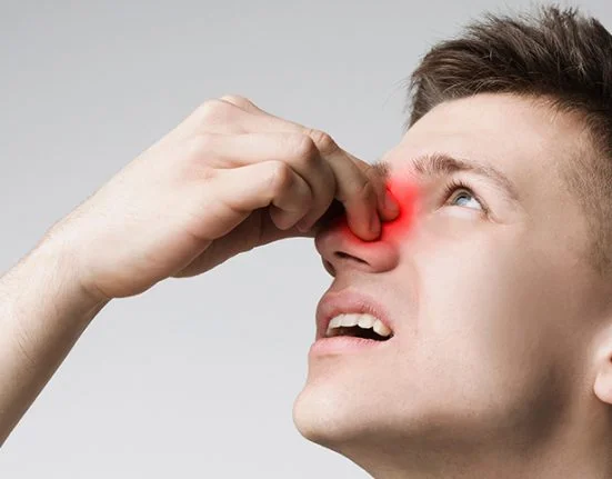 Man pinching nasal bridge with red highlighted sinus inflammation and facial pain