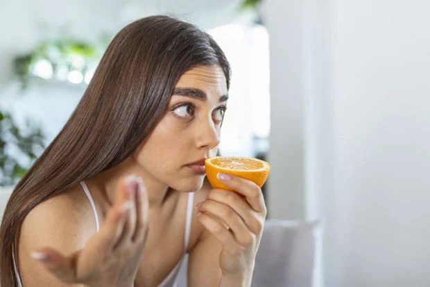 Woman unable to smell an orange experiencing loss of smell anosmia symptoms