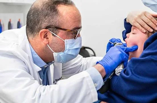 Pediatric ENT specialist examining a young child mouth and tonsils using medical lighting at Center of ENT Lahore