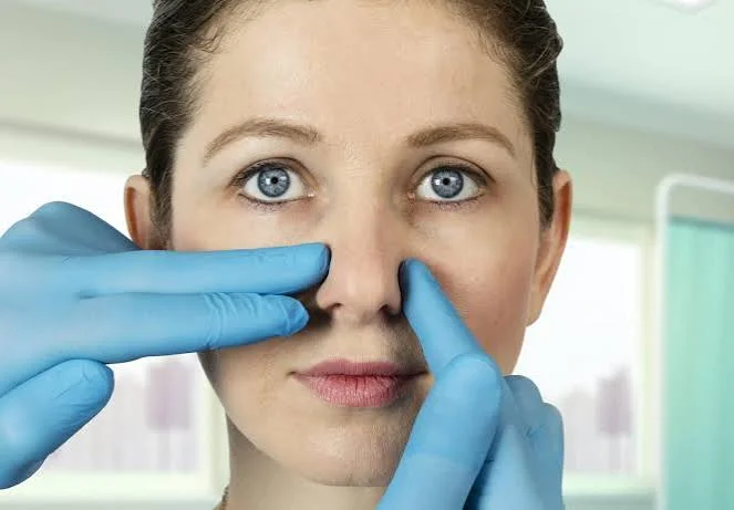 Surgeon in medical gloves palpating female nose bridge for septoplasty and airway assessment at Center of ENT Lahore