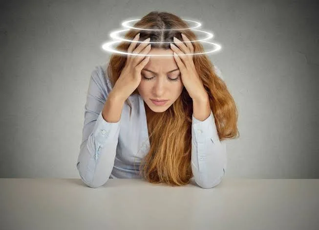 Woman holding head with spinning rings illustration experiencing vertigo and dizziness at Center of ENT Lahore