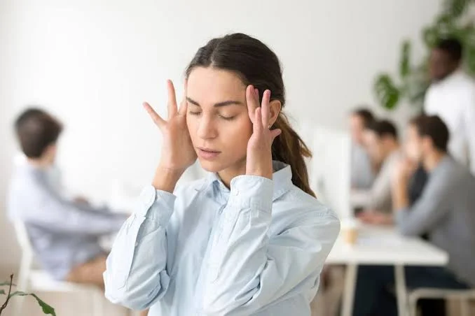 Stressed woman in office holding temples with headache and dizziness symptoms treated at Center of ENT Lahore